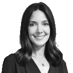 Black and white photo of a woman with shoulder-length dark hair, wearing a V-neck top and a necklace, smiling at the camera against a plain background.